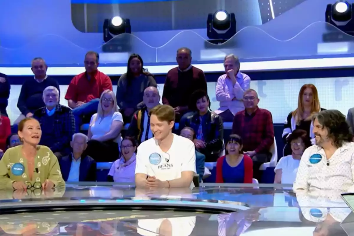María Esteve, Manu y J. J. Vaquero sentados en una mesa redonda en un programa de televisión con público sonriente al fondo. Captura de 'Pasapalabra' María Esteve, Manu y J. J. Vaquero sentados en una mesa redonda en un programa de televisión con público sonriente al fondo. Captura de 'Pasapalabra'