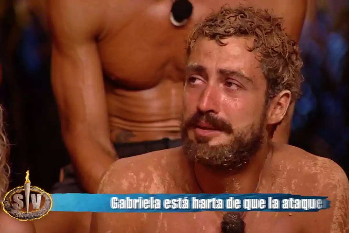 Joshua Velázquez está llorando mientras está cubierto de arena, con un micrófono en el pecho y una persona musculosa detrás de él. Captura de 'Supervivientes' Joshua Velázquez está llorando mientras está cubierto de arena, con un micrófono en el pecho y una persona musculosa detrás de él. Captura de 'Supervivientes'