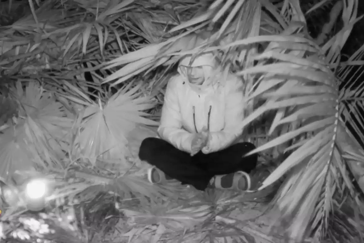 Montoya con capucha está sentada en el suelo rodeada de hojas de palmera en un ambiente oscuro. Captura de 'Supervivientes' Montoya con capucha está sentada en el suelo rodeada de hojas de palmera en un ambiente oscuro. Captura de 'Supervivientes'