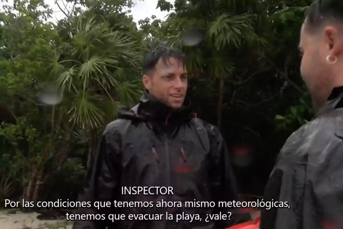 Montoya con impermeable negro habla con otra persona en un entorno de vegetación densa, mientras llueve. Captura de 'Supervivientes' Montoya con impermeable negro habla con otra persona en un entorno de vegetación densa, mientras llueve. Captura de 'Supervivientes'