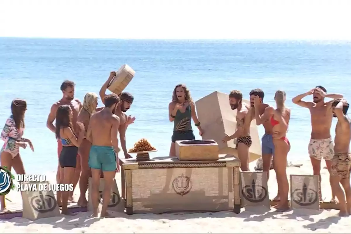 Grupo de personas en la playa participando en un desafío alrededor de una mesa con cajas y sacos. Captura de 'Supervivientes' Grupo de personas en la playa participando en un desafío alrededor de una mesa con cajas y sacos. Captura de 'Supervivientes'