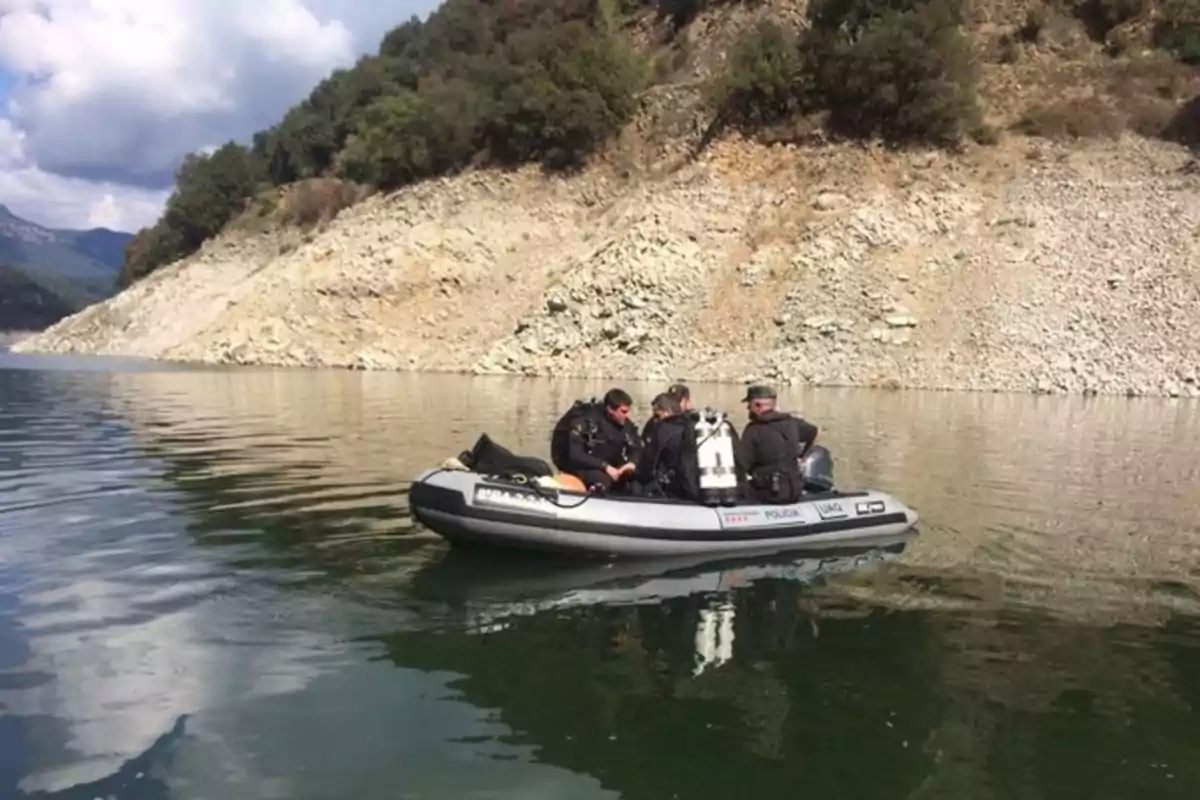 Un grupo de personas en un bote inflable sobre un lago rodeado de colinas rocosas y vegetación.