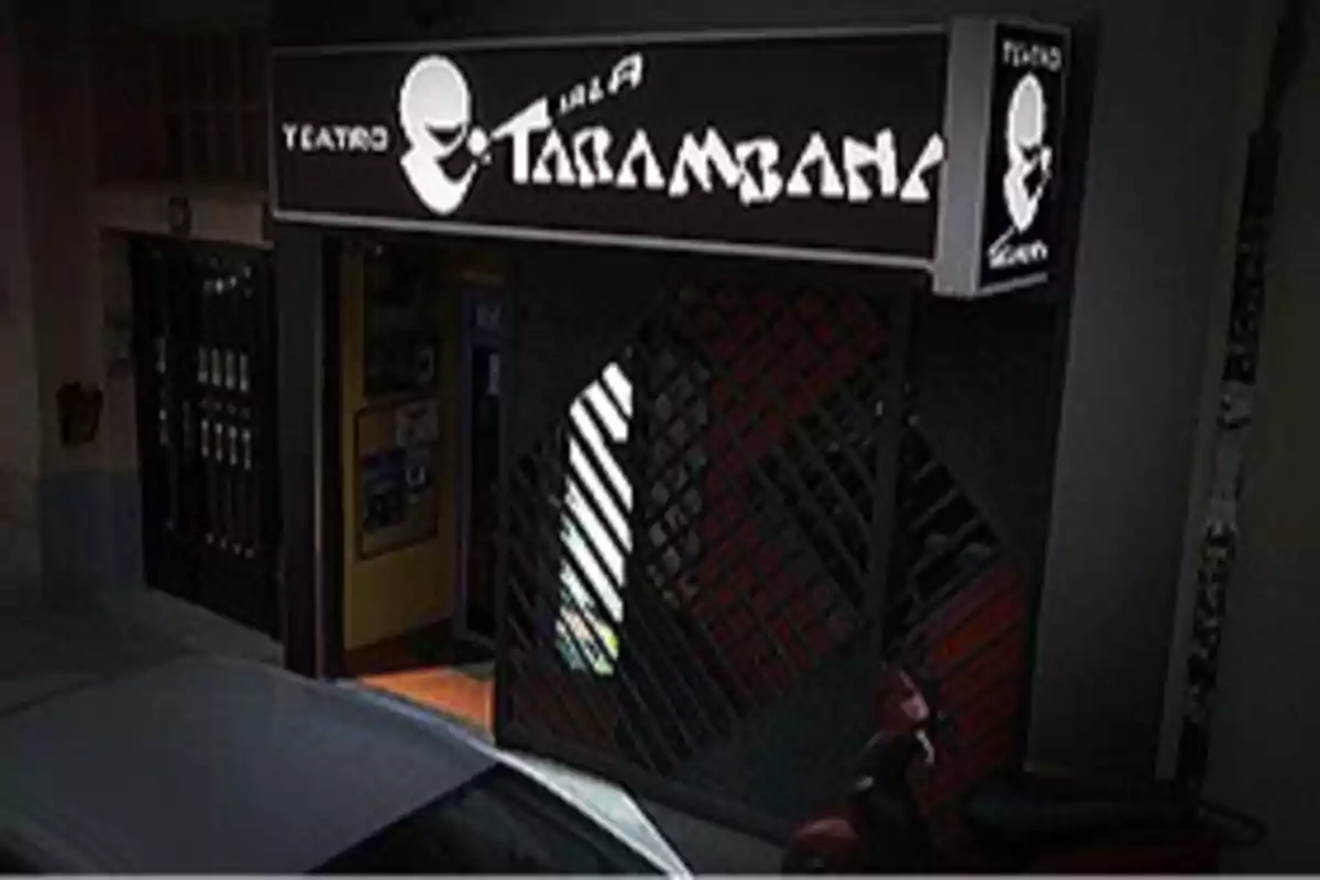 Entrada de un teatro con un cartel que dice "Sala Tarambana" y una puerta de rejas.