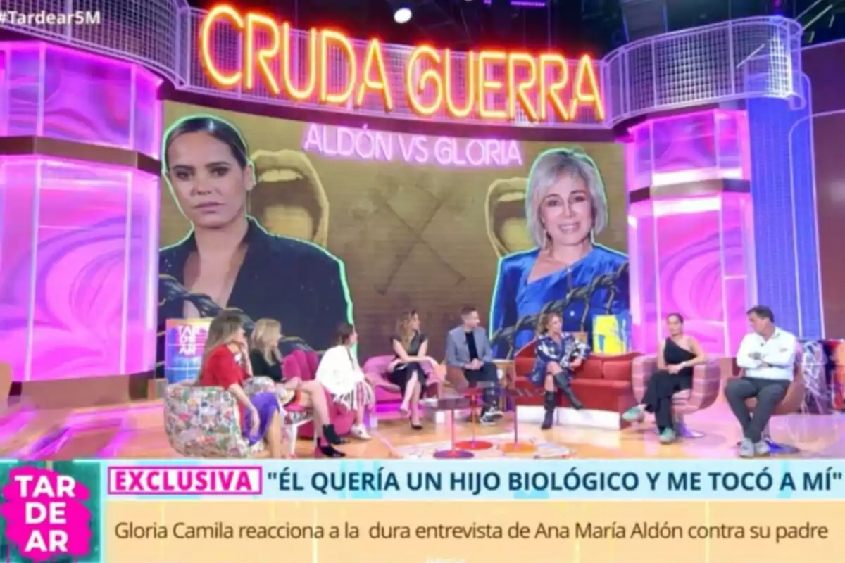 Un grupo de personas está sentado en un set de televisión colorido, con un gran cartel que dice Un grupo de personas está sentado en un set de televisión colorido, con un gran cartel que dice