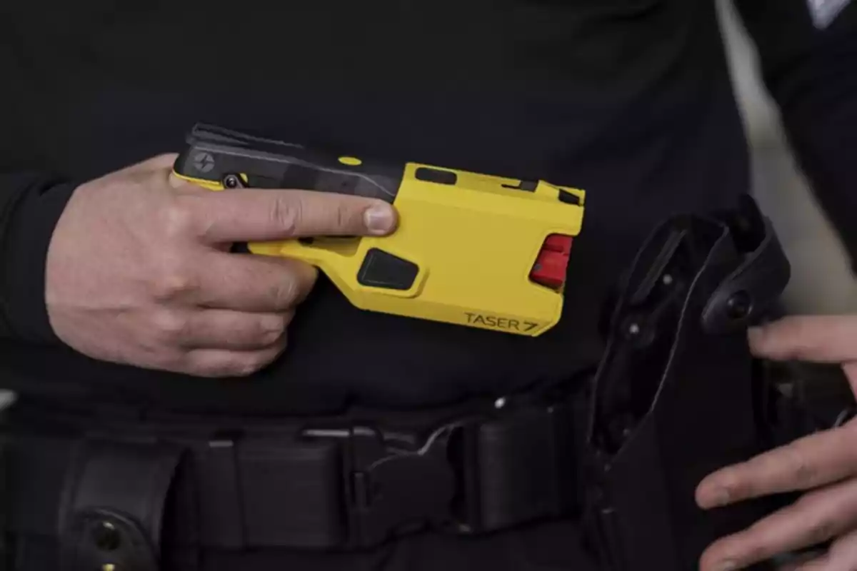 Una persona sosteniendo una pistola Taser amarilla.