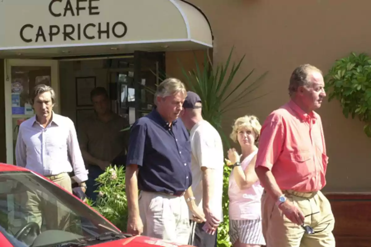 Varias personas salen de un café llamado "Café Capricho" en un día soleado.