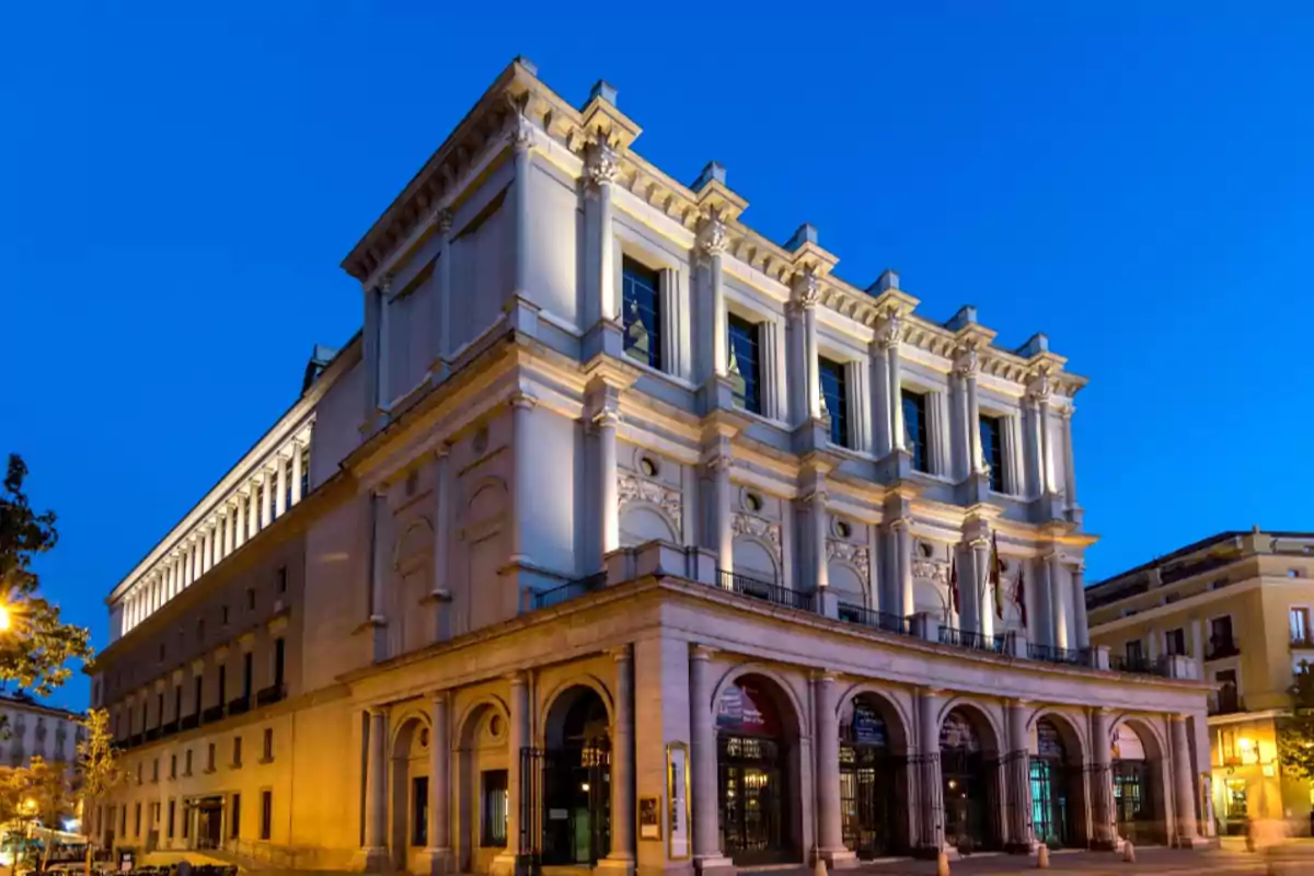 Edificio histórico iluminado al anochecer con cielo azul claro.