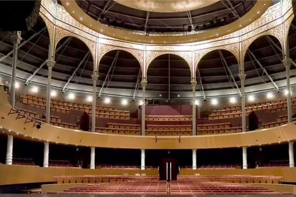 Interior de un teatro con asientos vacíos y una estructura de arcos decorativos en el techo.