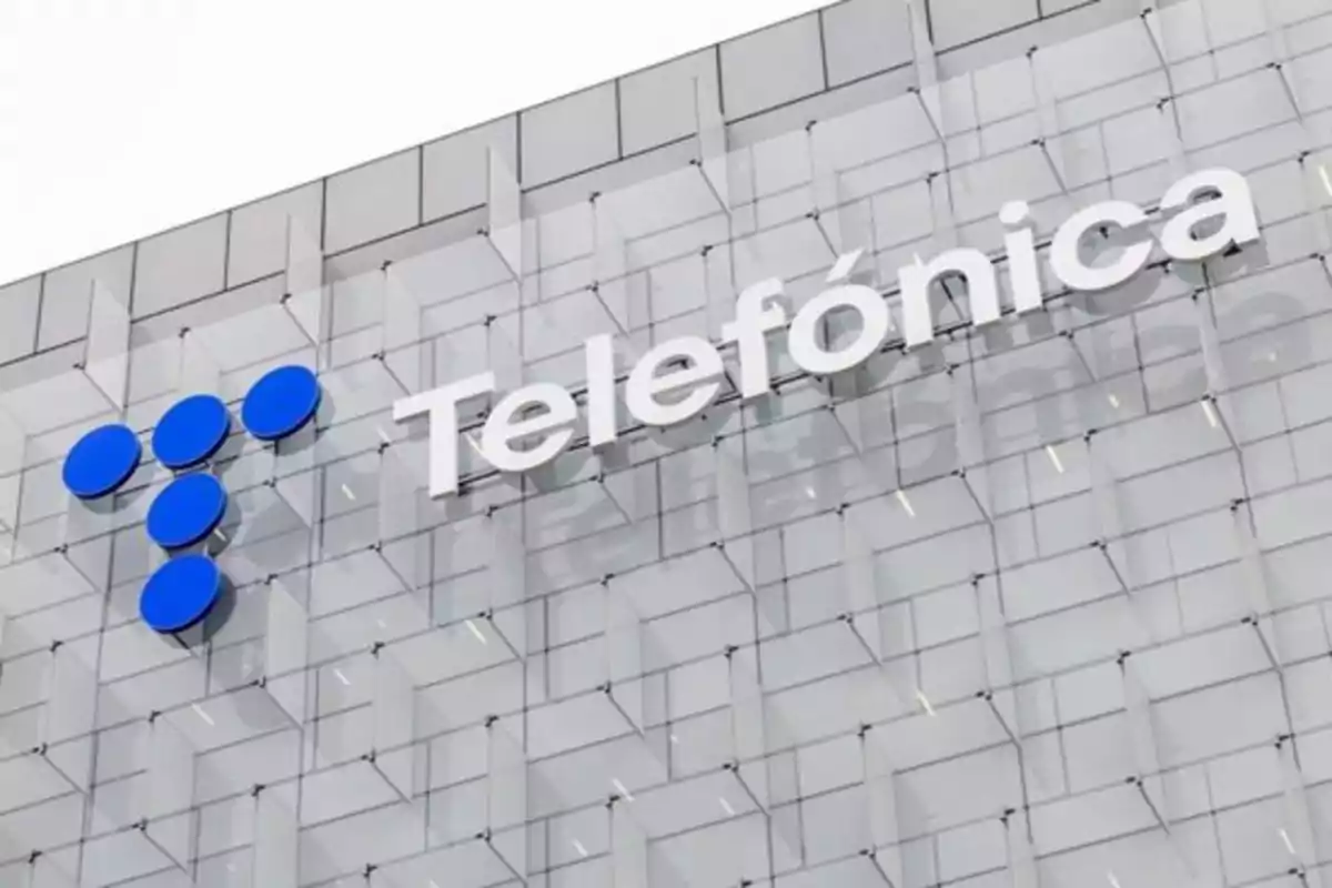 Fachada de un edificio moderno con el logo y el nombre de Telefónica en letras grandes blancas Fachada de un edificio moderno con el logo y el nombre de Telefónica en letras grandes blancas