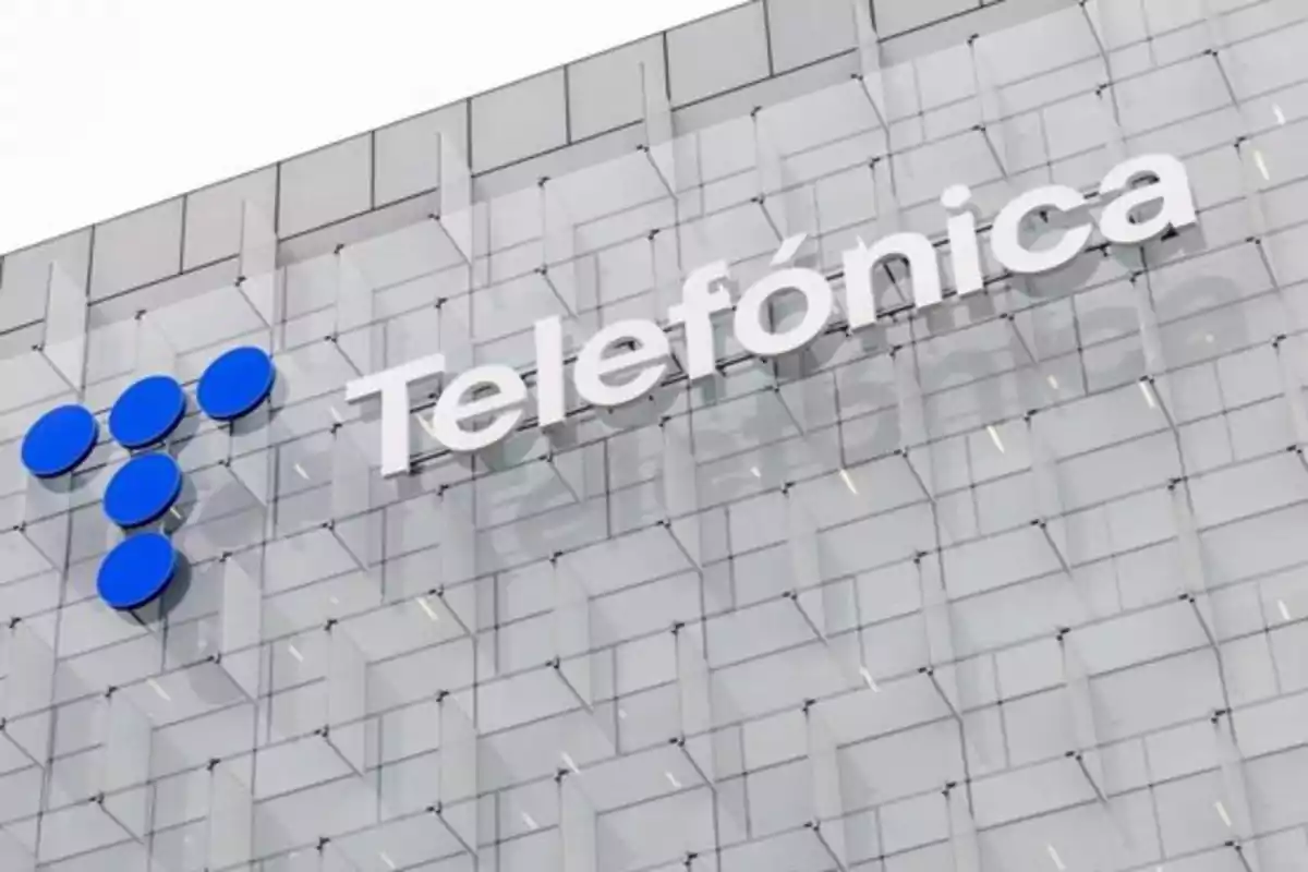 Fachada de un edificio moderno con el logo y nombre de Telefónica en letras grandes blancas Fachada de un edificio moderno con el logo y nombre de Telefónica en letras grandes blancas
