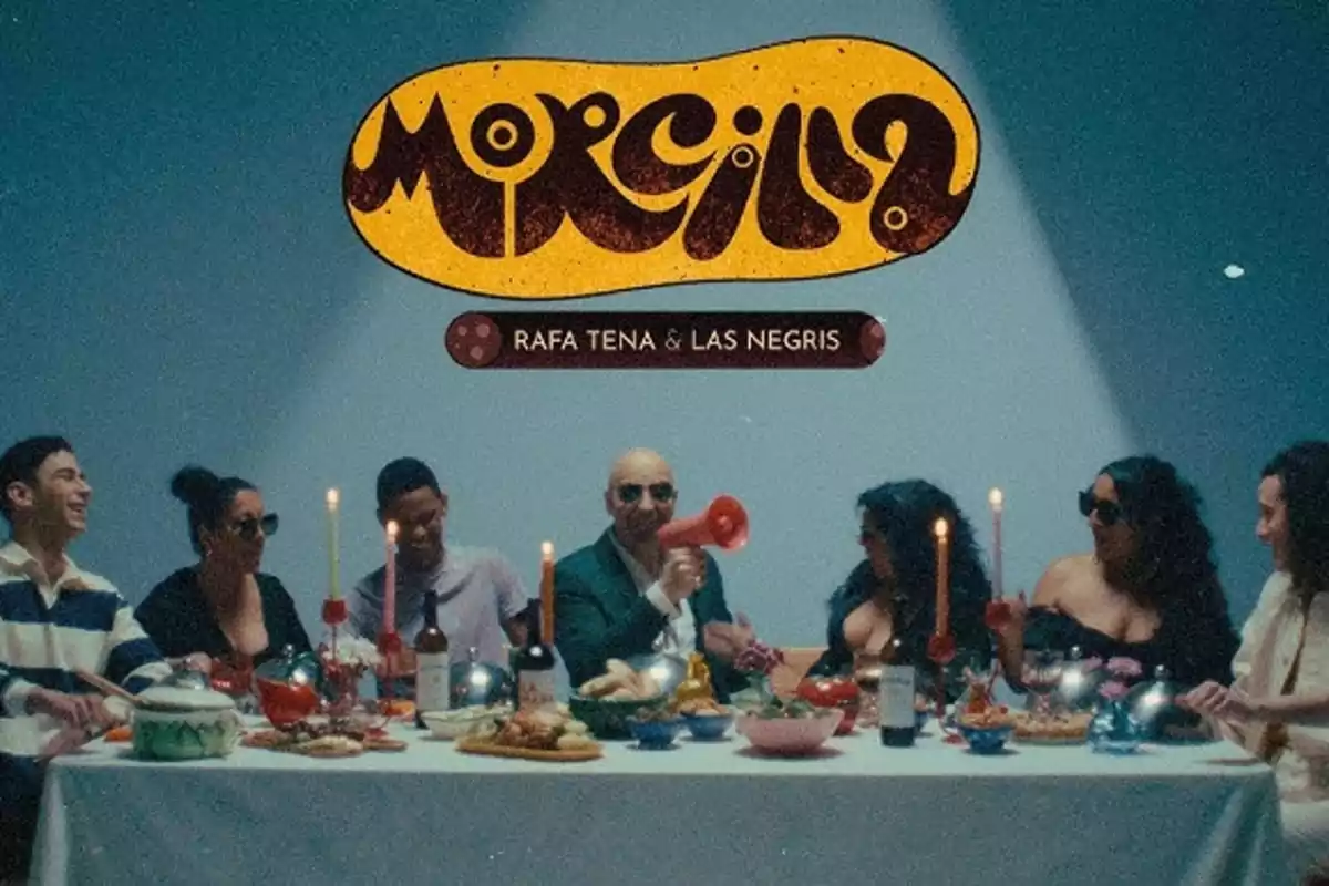 Un grupo de personas sentadas alrededor de una mesa con comida y velas, con un cartel que dice "Morcilla" y "Rafa Tena & Las Negris" arriba.