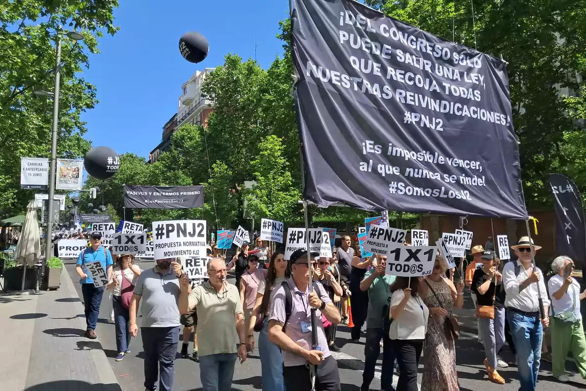 Manifestación en la calle con personas sosteniendo pancartas y carteles que piden la aprobación de una ley, rodeados de árboles y bajo un cielo despejado Manifestación en la calle con personas sosteniendo pancartas y carteles que piden la aprobación de una ley, rodeados de árboles y bajo un cielo despejado