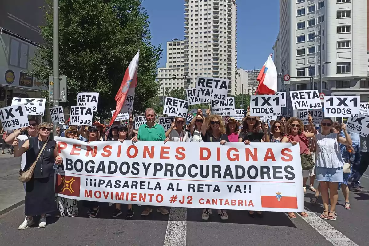 Grupo de personas manifestándose en la calle con pancartas y un cartel grande que exige pensiones dignas para abogados y procuradores bajo un cielo soleado en una ciudad Grupo de personas manifestándose en la calle con pancartas y un cartel grande que exige pensiones dignas para abogados y procuradores bajo un cielo soleado en una ciudad