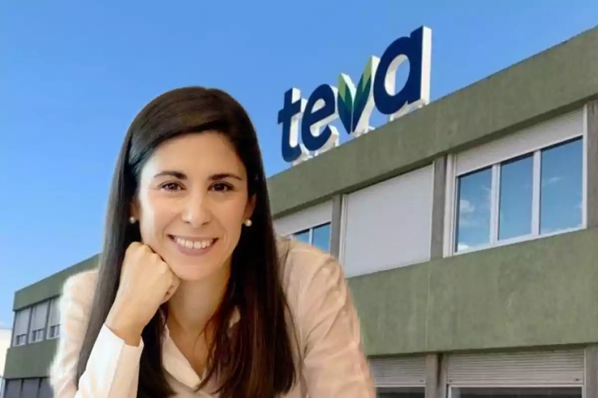 Mujer sonriente de cabello largo y oscuro frente a un edificio con el logo de Teva en la parte superior bajo un cielo azul
