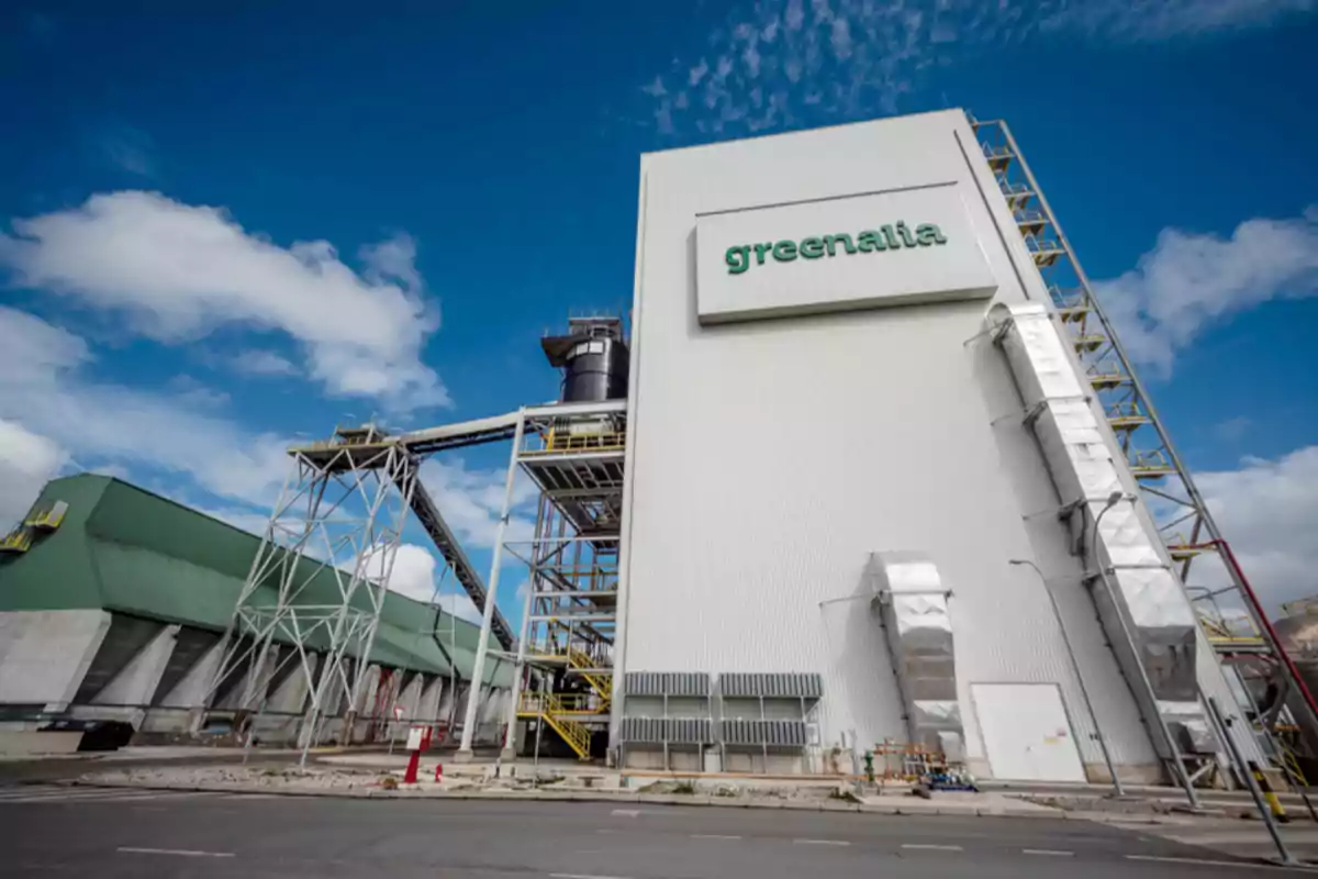 Edificio industrial de gran tamaño con el logo de greenalia en la fachada bajo un cielo azul con nubes