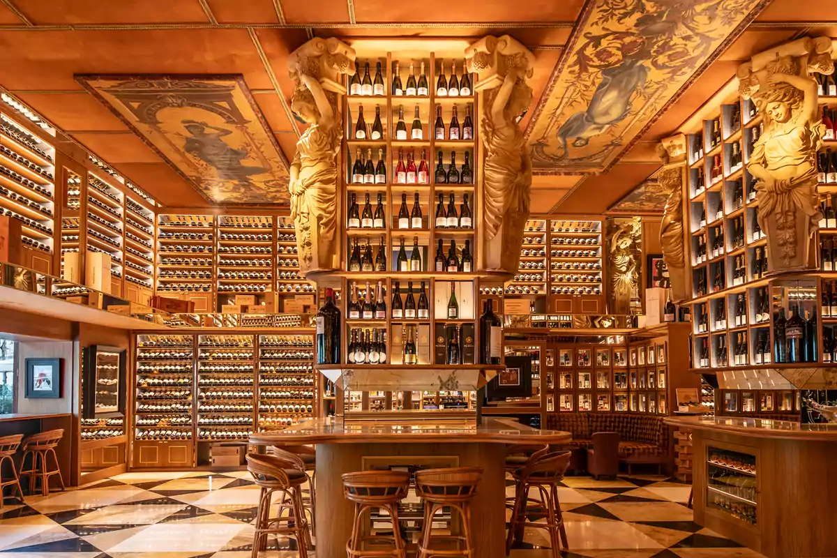 Un elegante bar de vinos con estanterías llenas de botellas, decorado con esculturas clásicas y un techo adornado con pinturas artísticas. Un elegante bar de vinos con estanterías llenas de botellas, decorado con esculturas clásicas y un techo adornado con pinturas artísticas.