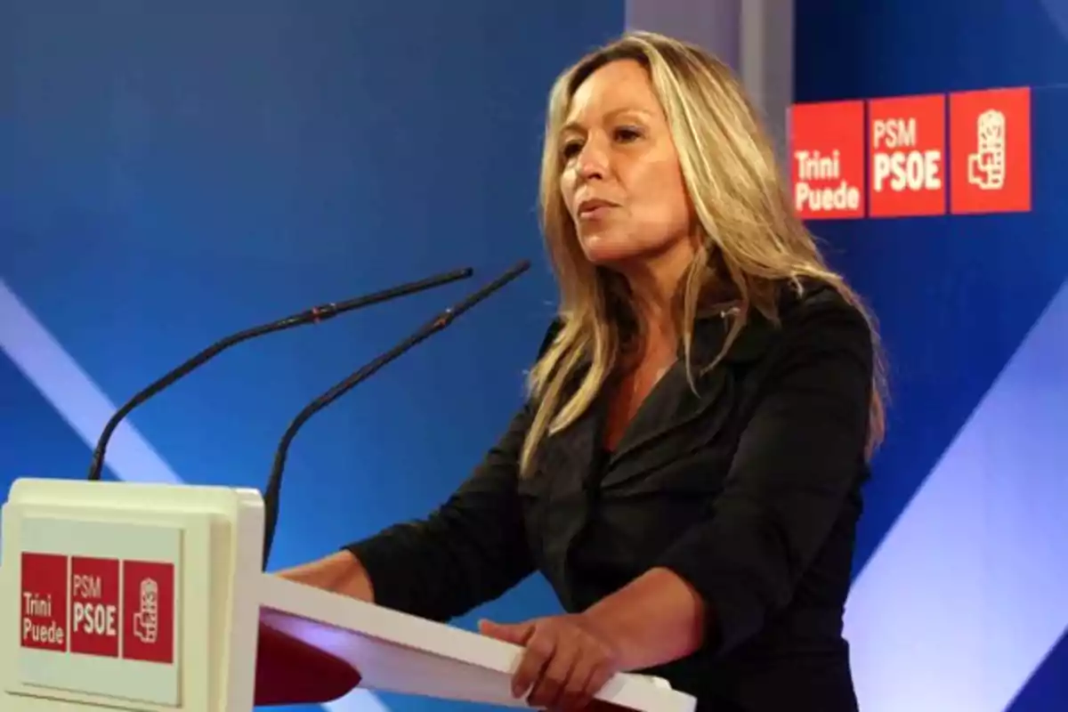 Mujer rubia hablando en un podio con micrófonos en un evento del PSOE Mujer rubia hablando en un podio con micrófonos en un evento del PSOE