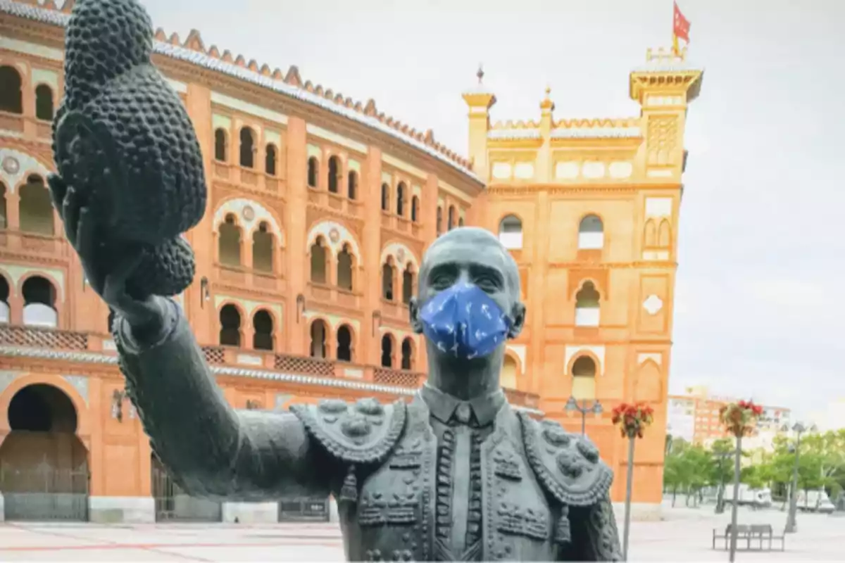 Estatua de un torero con mascarilla frente a una plaza de toros. Estatua de un torero con mascarilla frente a una plaza de toros.