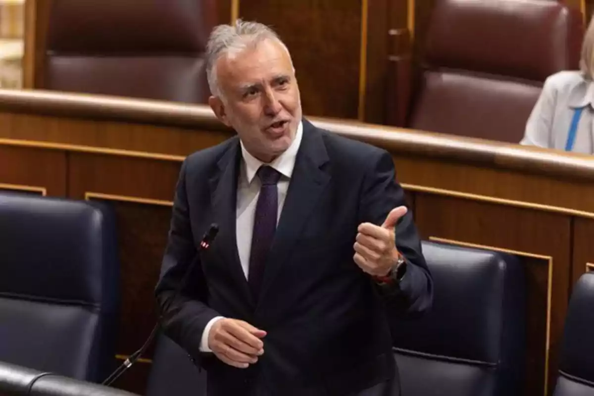 Un hombre de traje hablando en un parlamento con gesto enfático.