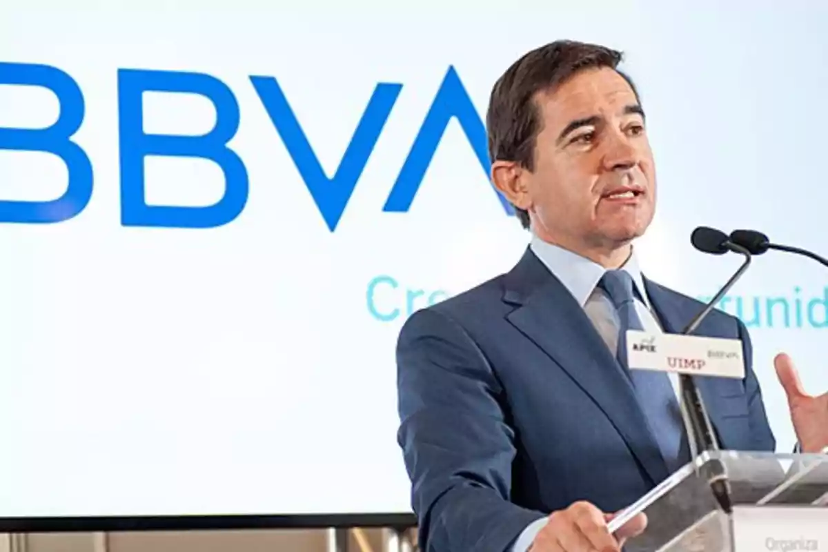 Un hombre en traje hablando en un podio con el logo de BBVA en el fondo.