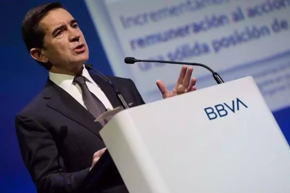 Un hombre en traje hablando en un podio con el logo de BBVA.