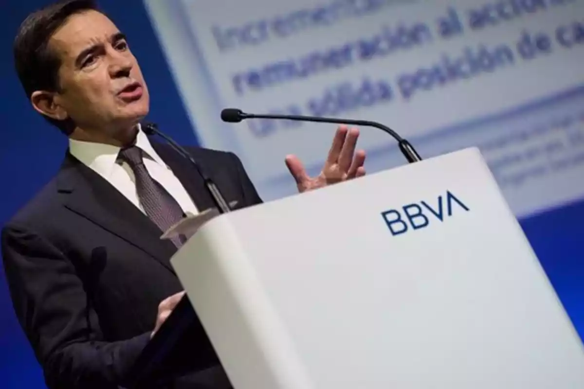 Hombre en traje dando un discurso en un podio con el logo de BBVA.