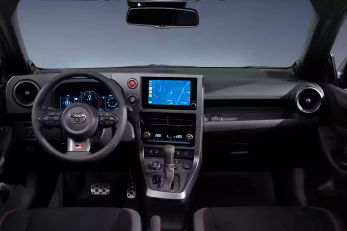 Interior de un automóvil moderno con volante multifuncional, pantalla táctil central y controles de climatización. Interior de un automóvil moderno con volante multifuncional, pantalla táctil central y controles de climatización.