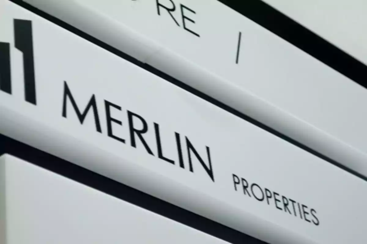Letrero blanco con el texto Merlin Properties y un logotipo geométrico negro Letrero blanco con el texto Merlin Properties y un logotipo geométrico negro