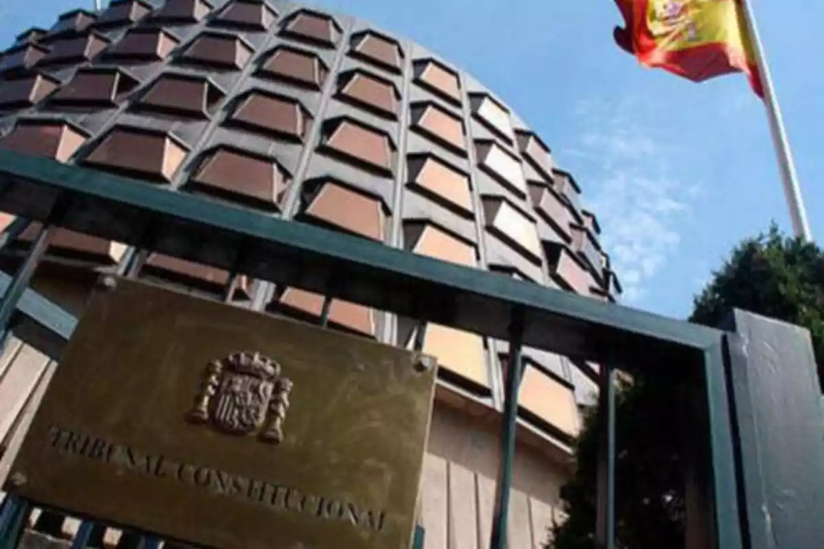 Edificio del Tribunal Constitucional de España con una bandera española ondeando.