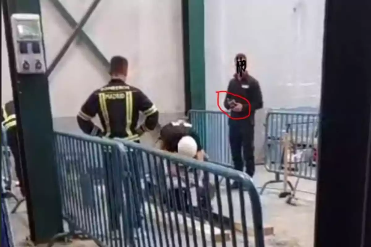 Un grupo de personas con uniformes de bomberos está trabajando en una zona cercada con vallas metálicas en un entorno industrial.