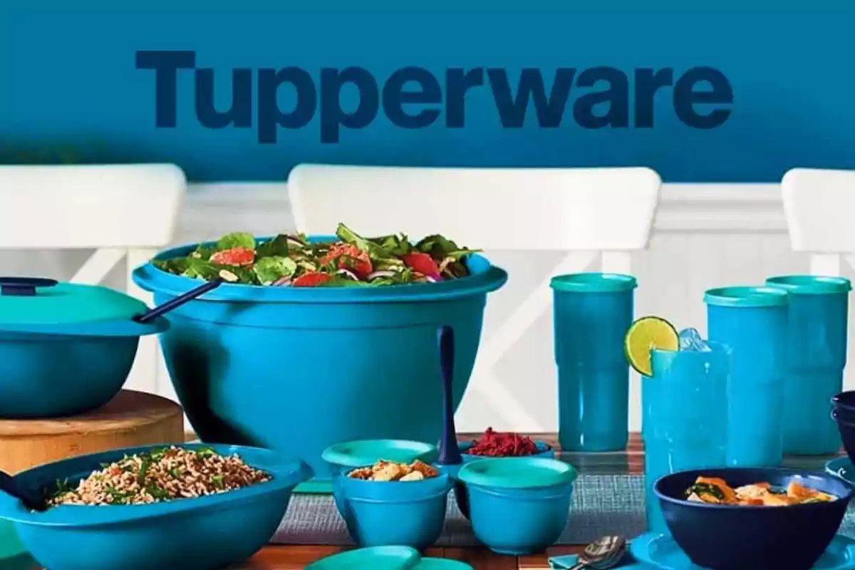 Utensilios de cocina Tupperware de color azul en una mesa con ensaladas y bebidas.