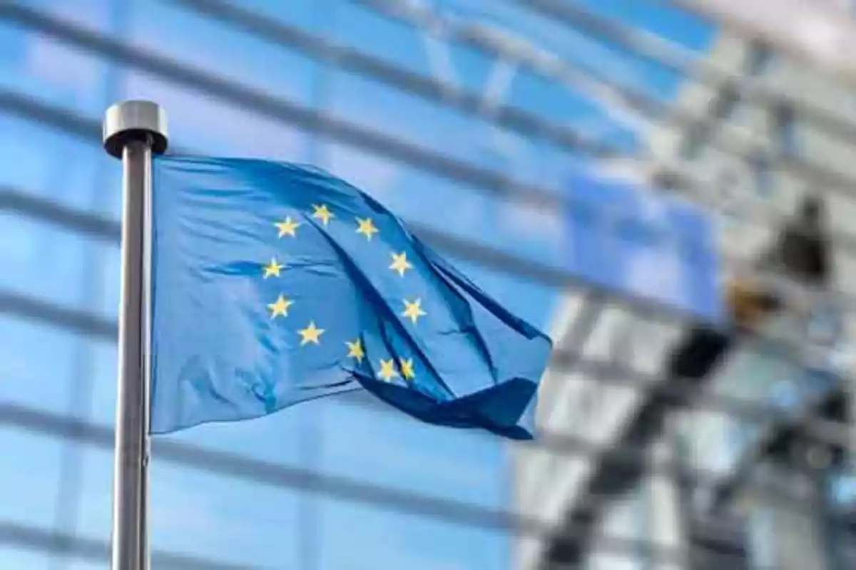Bandera de la Unión Europea ondeando frente a un edificio moderno