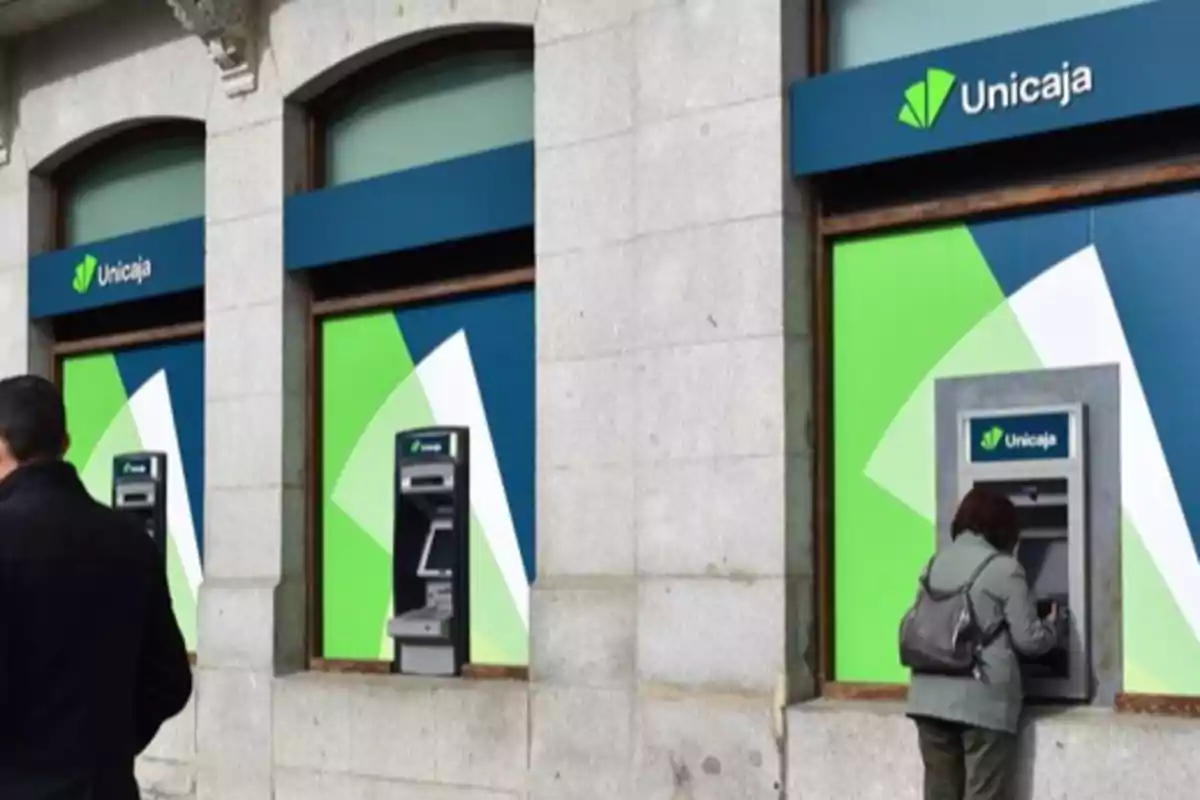 Personas utilizando cajeros automáticos en una sucursal de Unicaja. Personas utilizando cajeros automáticos en una sucursal de Unicaja.