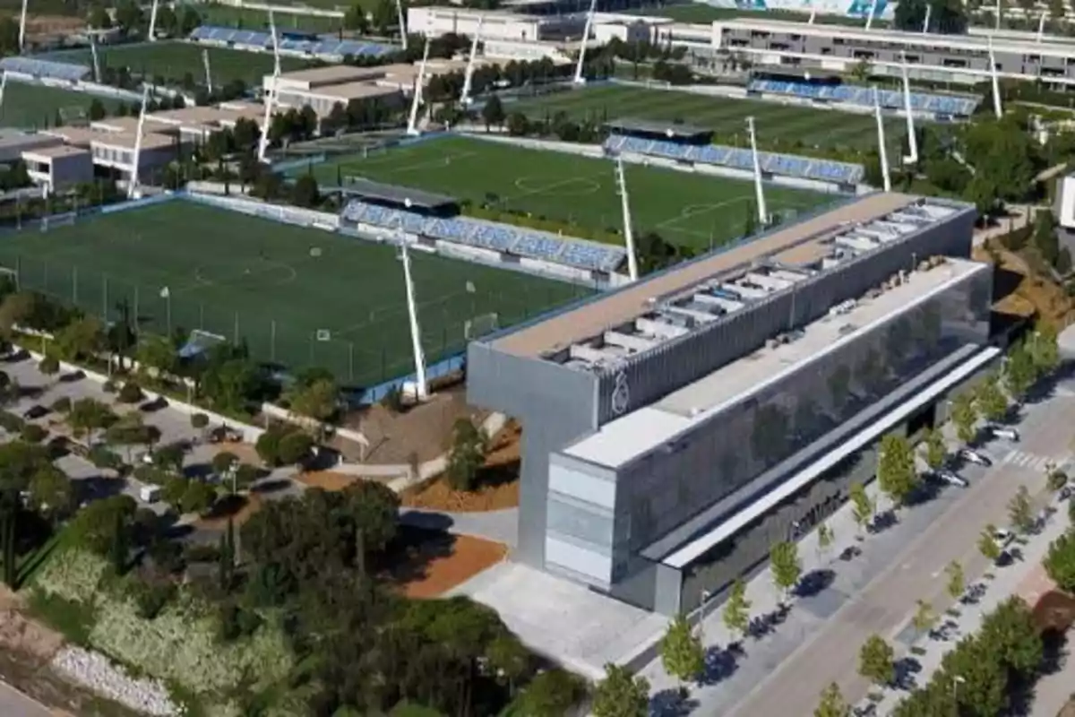 Vista aérea de un complejo deportivo con varios campos de fútbol rodeados de edificios y áreas verdes. Vista aérea de un complejo deportivo con varios campos de fútbol rodeados de edificios y áreas verdes.