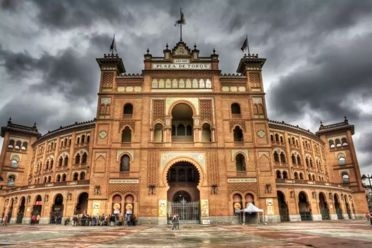 Fachada de una plaza de toros con cielo nublado.