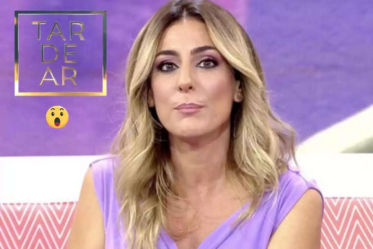 Una persona con cabello rubio y ondulado, vestida de lila, aparece en un programa de televisión con un fondo morado y un logotipo que dice "TARDEAR".