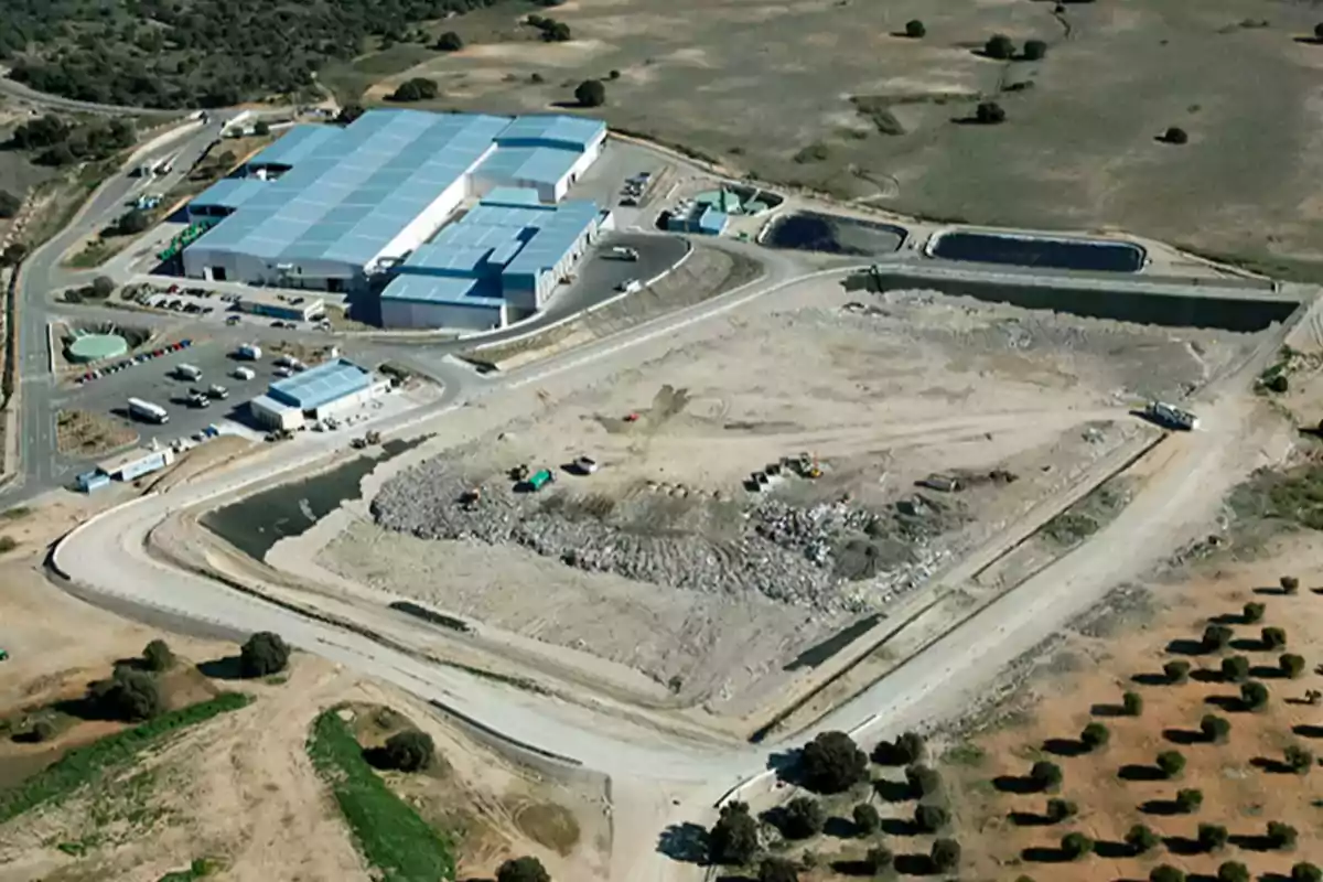 Vista aérea de una planta de tratamiento de residuos rodeada de áreas verdes y caminos.