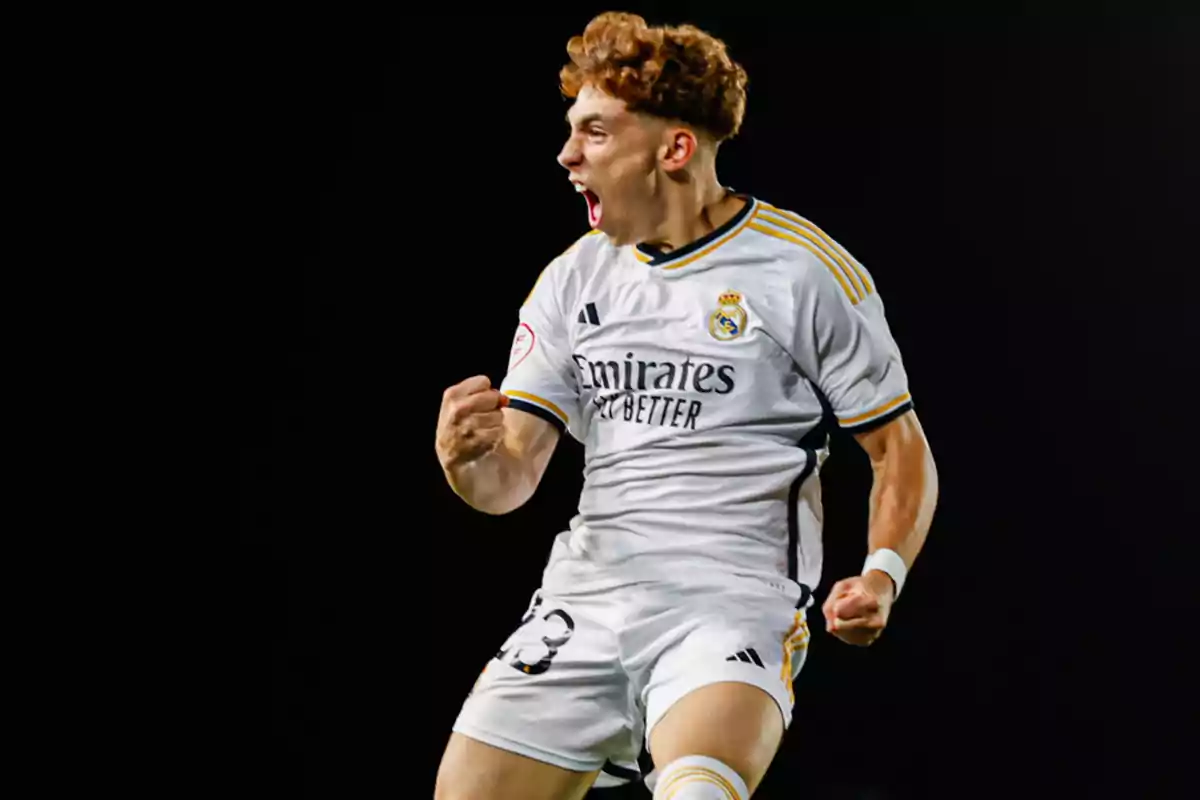 Jugador de fútbol celebrando con emoción mientras viste el uniforme blanco del Real Madrid.