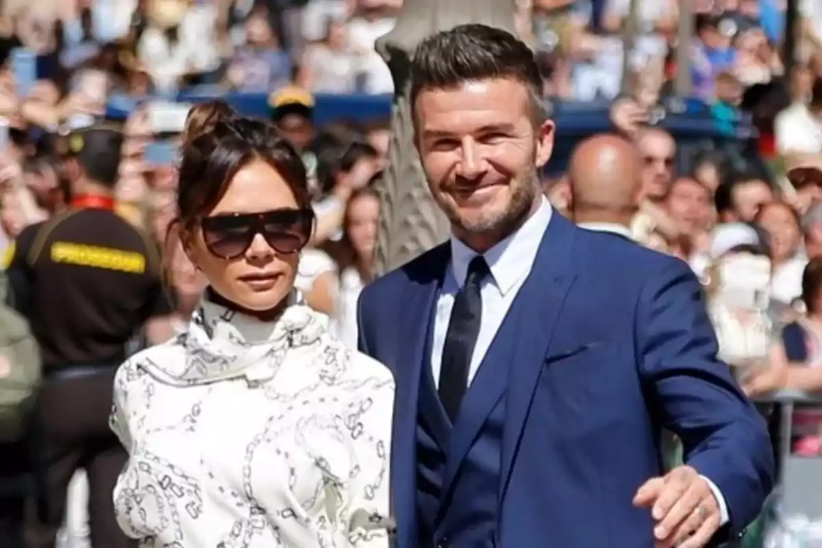 Una pareja elegante caminando entre una multitud en un evento al aire libre. Una pareja elegante caminando entre una multitud en un evento al aire libre.