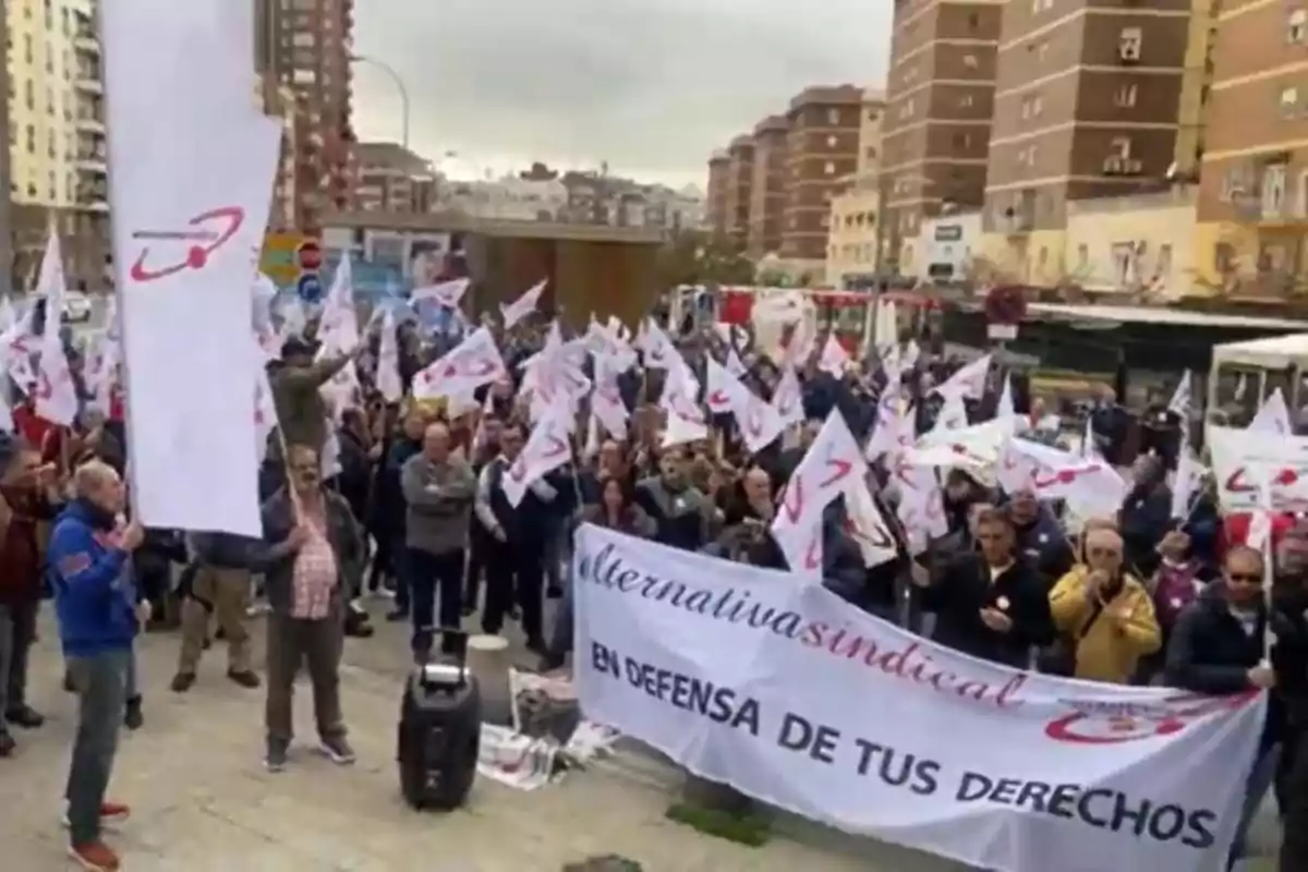 Un grupo de personas se manifiesta en la calle con banderas y una pancarta que dice 