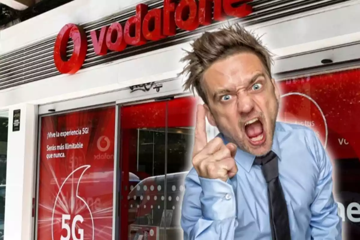 Un hombre con expresión de enojo y señalando con el dedo frente a una tienda de Vodafone.