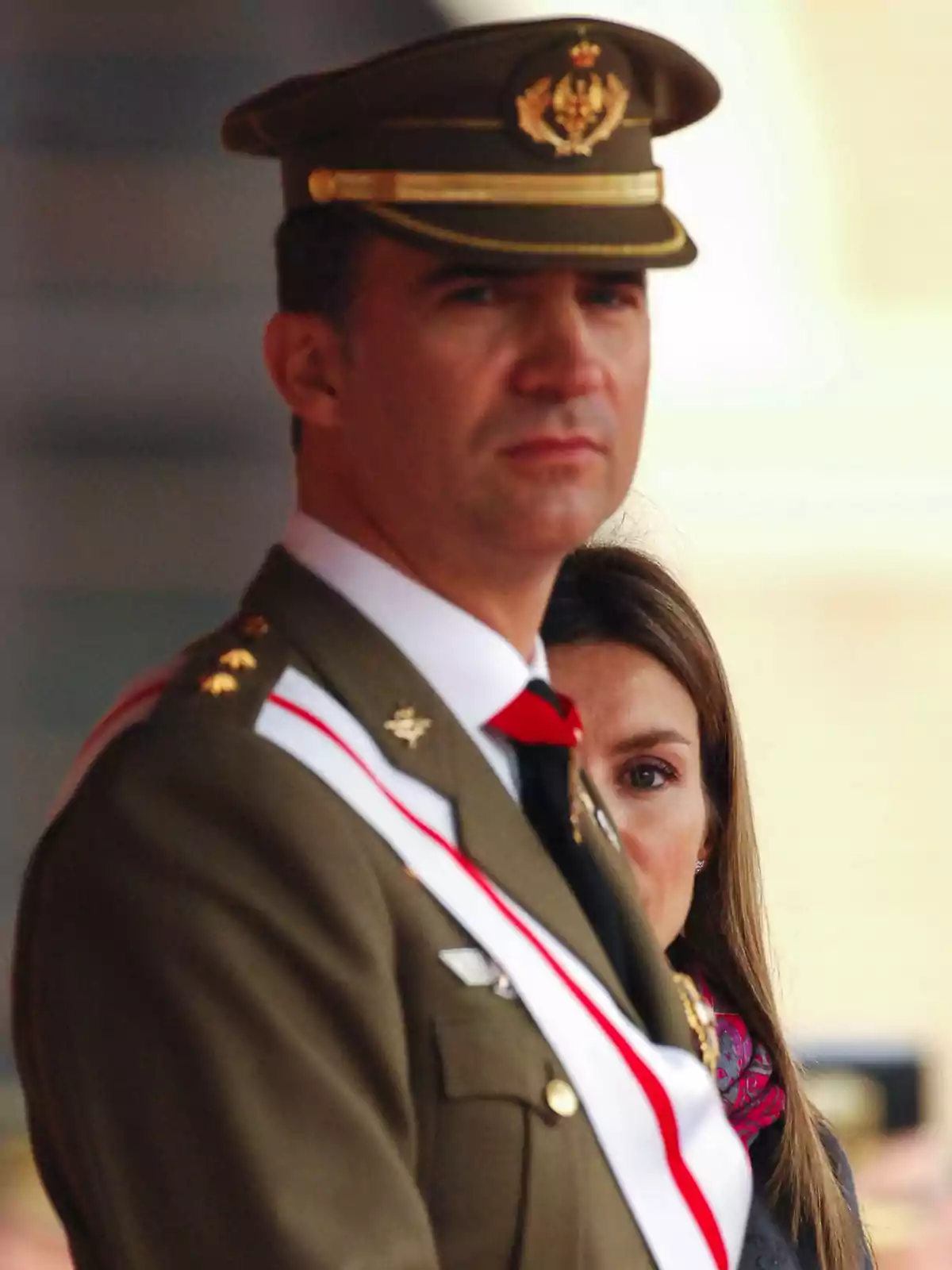 Un hombre con uniforme militar y una mujer detrás de él.