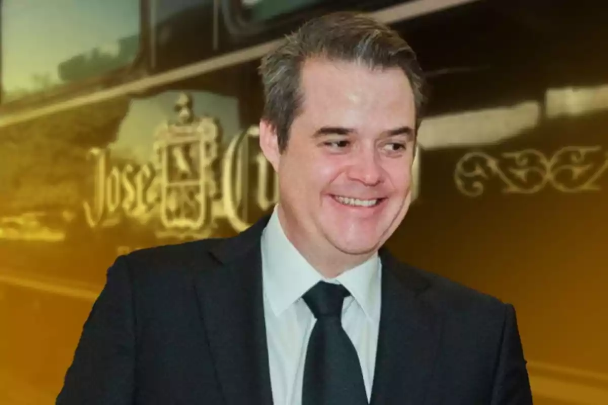 Hombre sonriendo con traje oscuro y corbata frente a un fondo con el logo de José Cuervo.