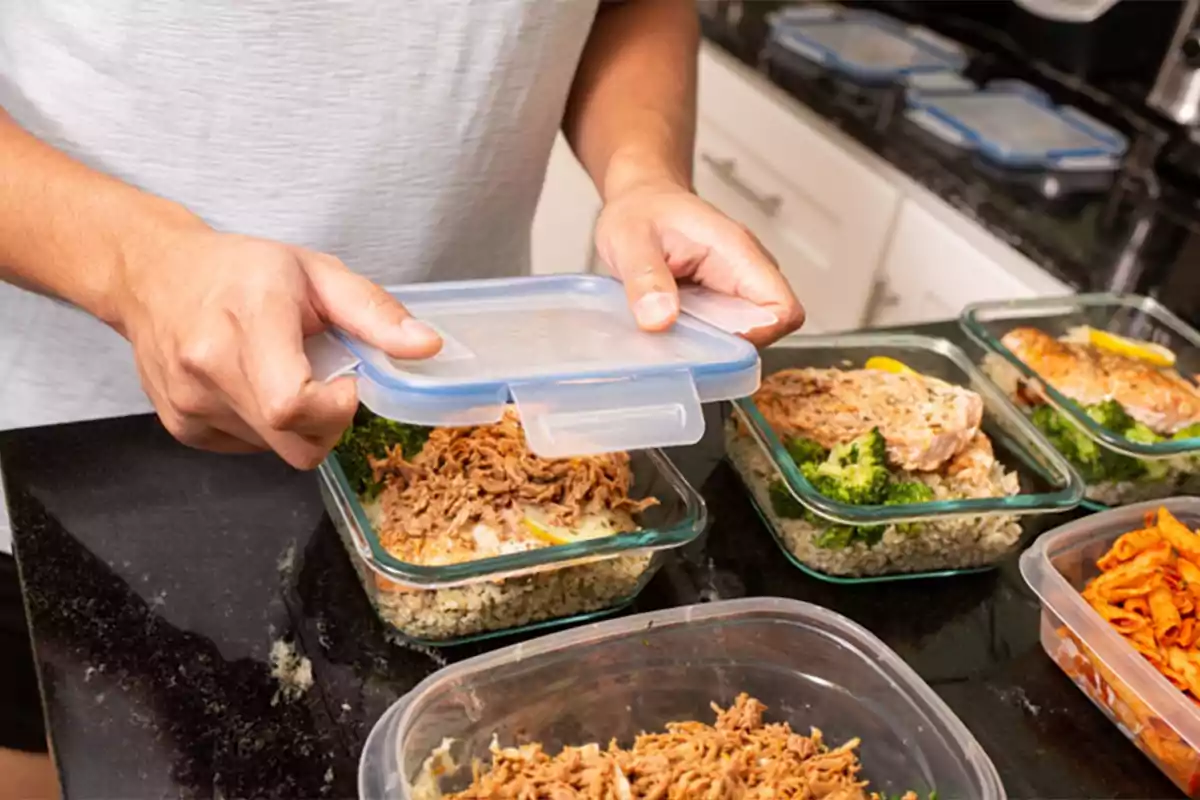 Persona cerrando un recipiente de vidrio con comida preparada en una cocina.