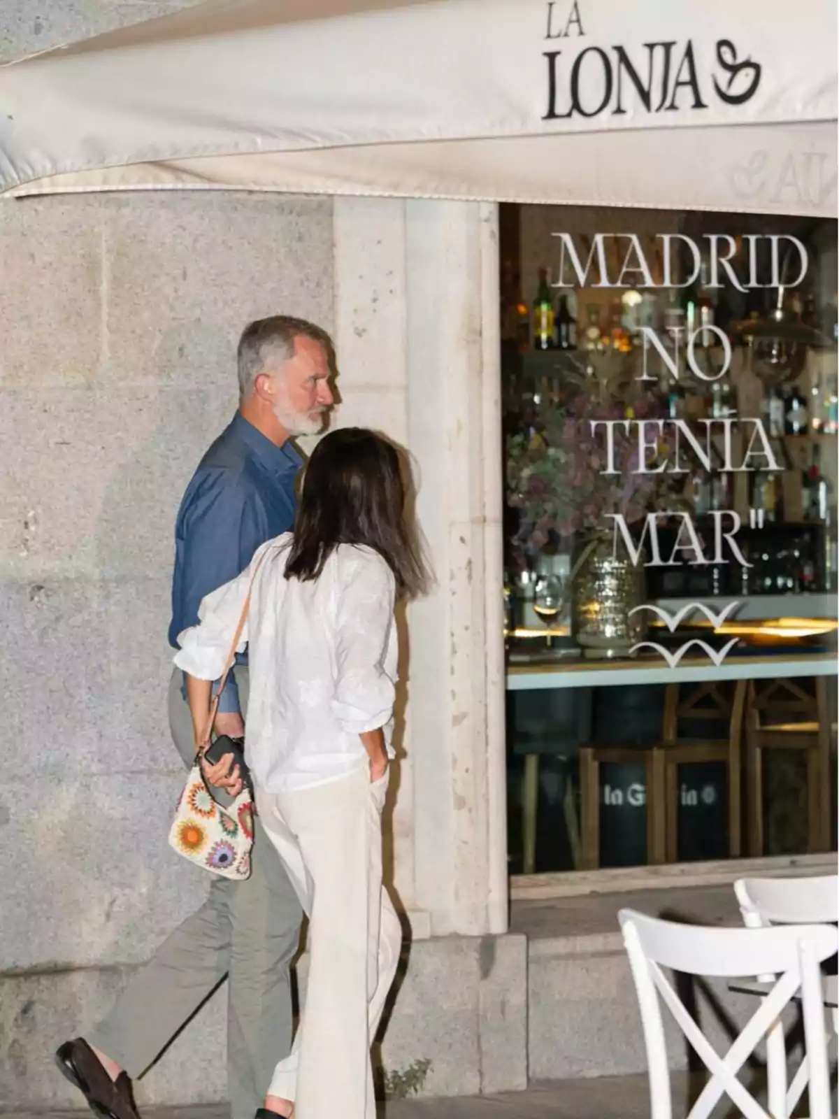 Una pareja camina frente a un restaurante llamado 