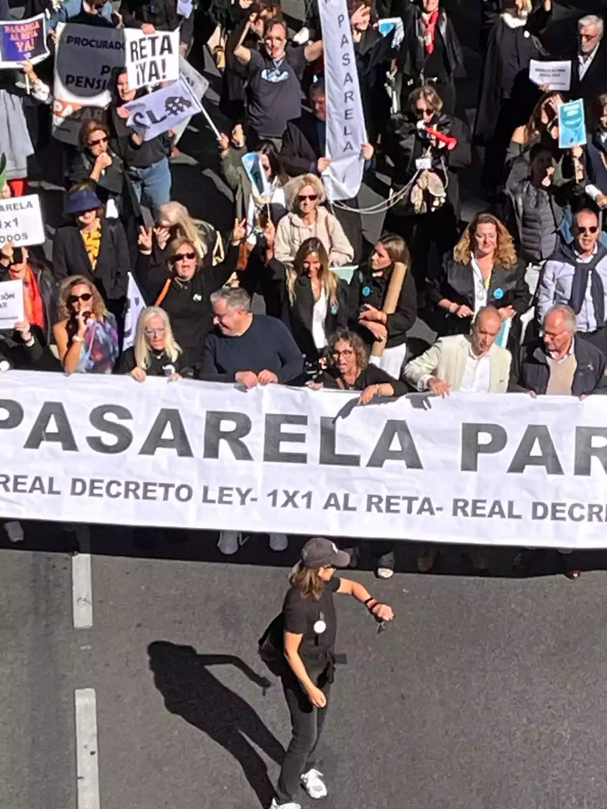 Manifestación con personas sosteniendo pancartas y un gran cartel que dice 