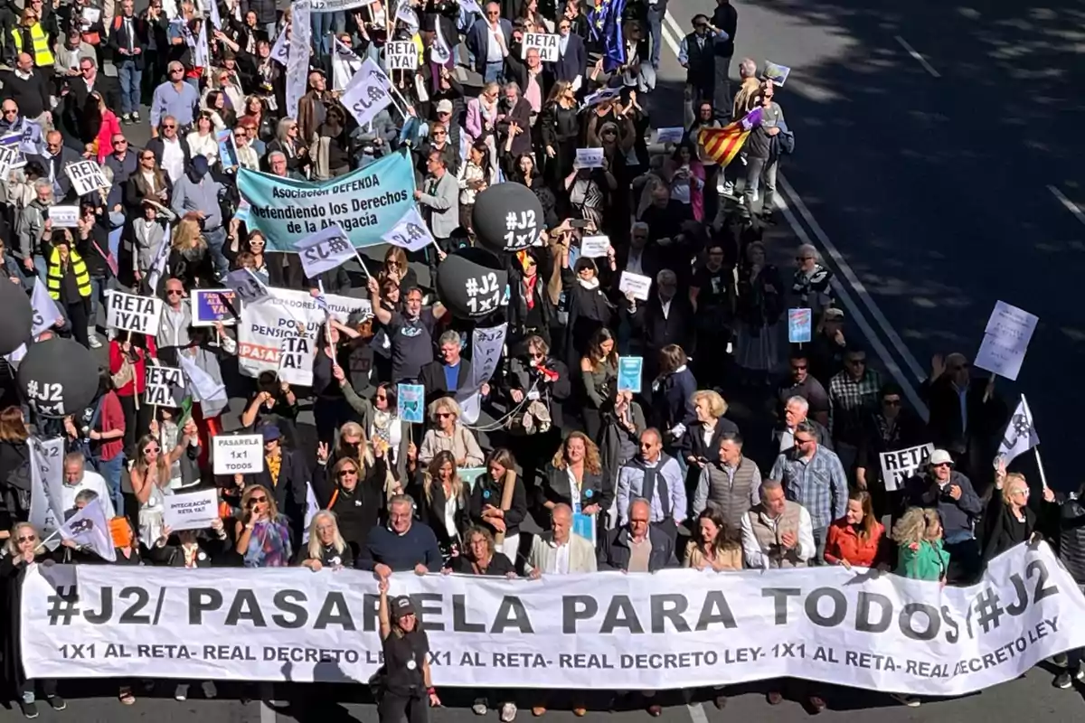 Una multitud de personas participa en una manifestación, sosteniendo pancartas y carteles con mensajes como "RETA ¡YA!", "PASARELA 1x1 TODOS" y "Defendiendo los Derechos de la Abogacía".