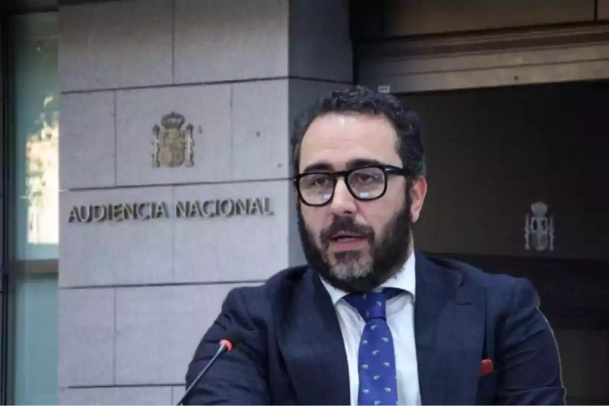 Un hombre con barba y gafas habla frente a un edificio con el letrero "Audiencia Nacional".