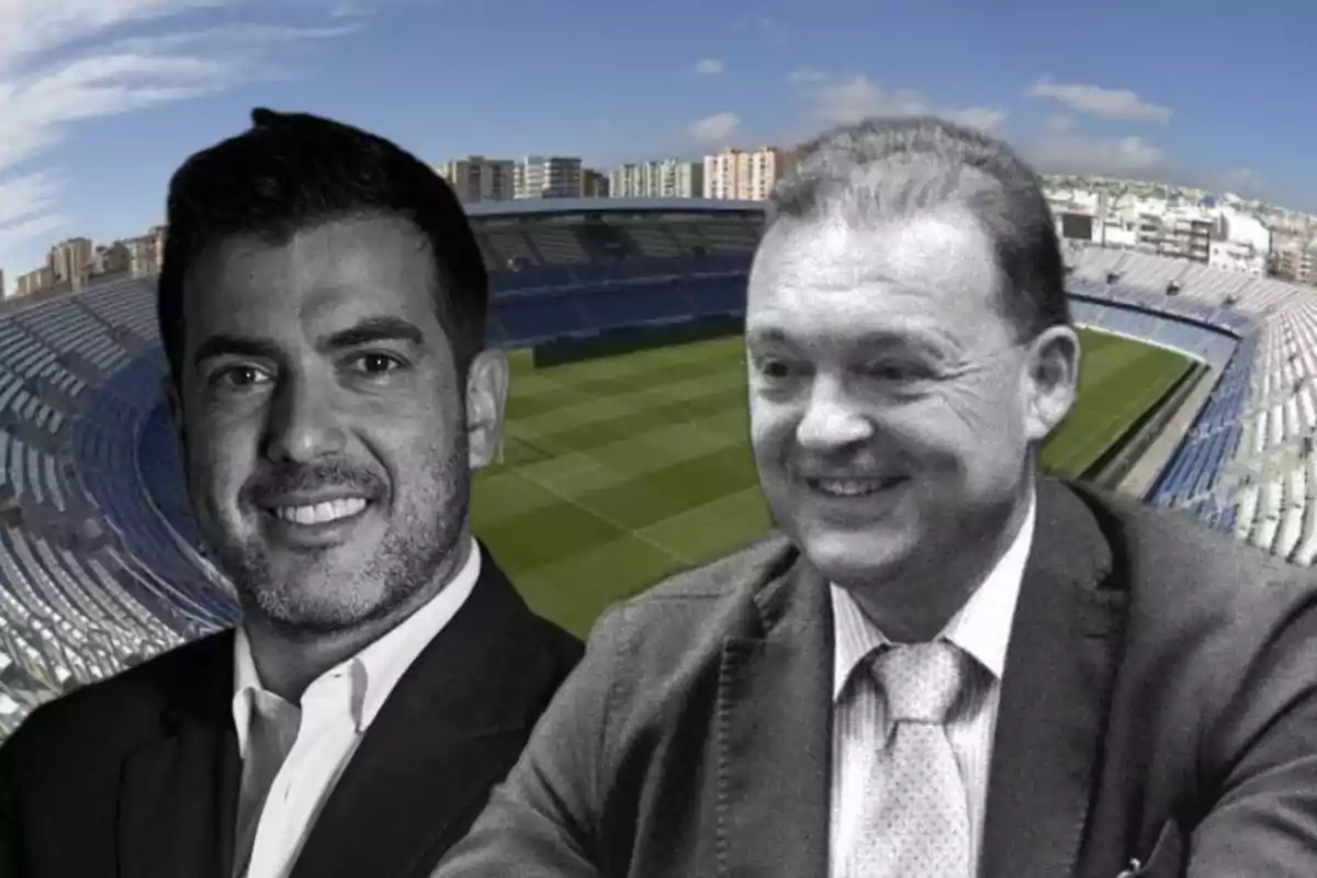 Dos hombres en traje frente a un estadio de fútbol.