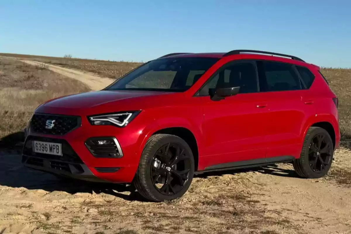 Un SEAT Ateca FR Special Edition rojo estacionado en un camino de tierra bajo un cielo despejado.